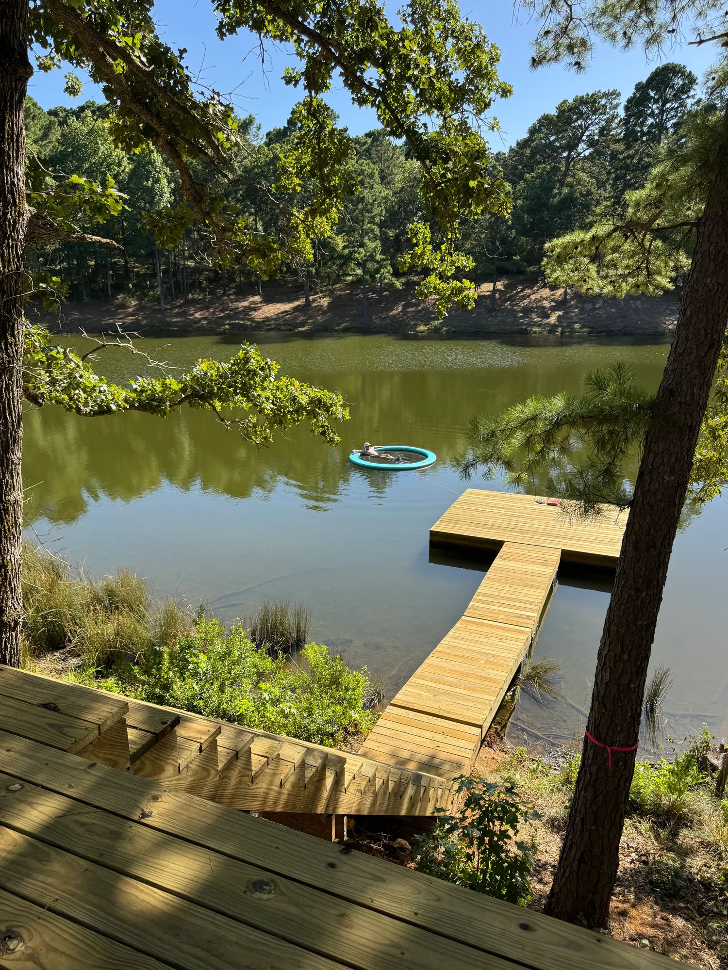 Wooden steps and a walkway leading to a dock on the tree-lined private lake